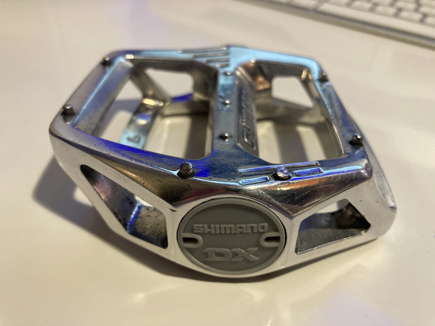 Graue Shimano-DX-kompatible Staubkappe am verchromten Pedal mit sichtbaren vorhandenen Gebrauchsspuren