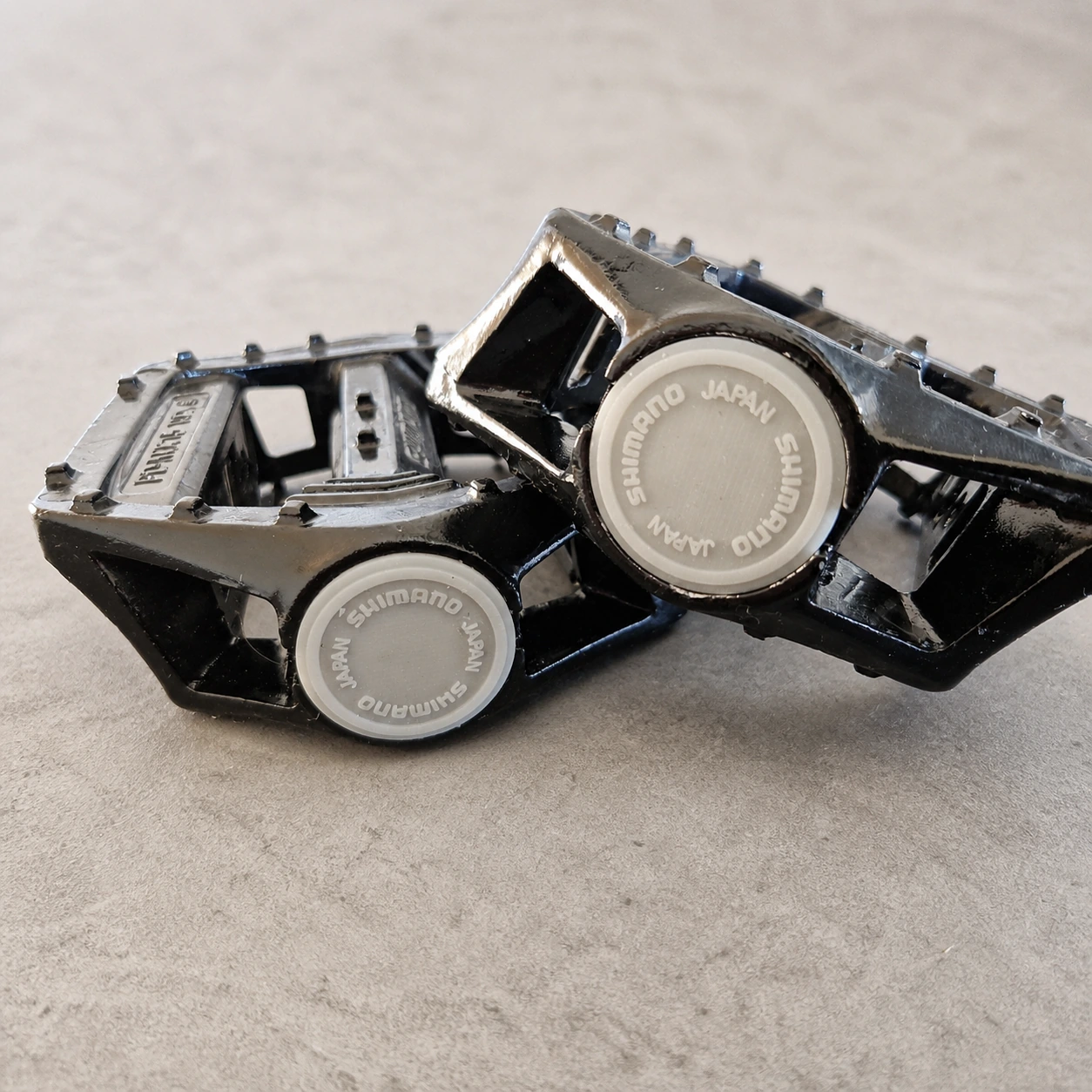 Zwei schwarze Shimano-PD-MX15-Pedale mit montierten grauen Ersatzkappen der älteren Ausführung auf dem vorhandenen Etsy-Produktfoto