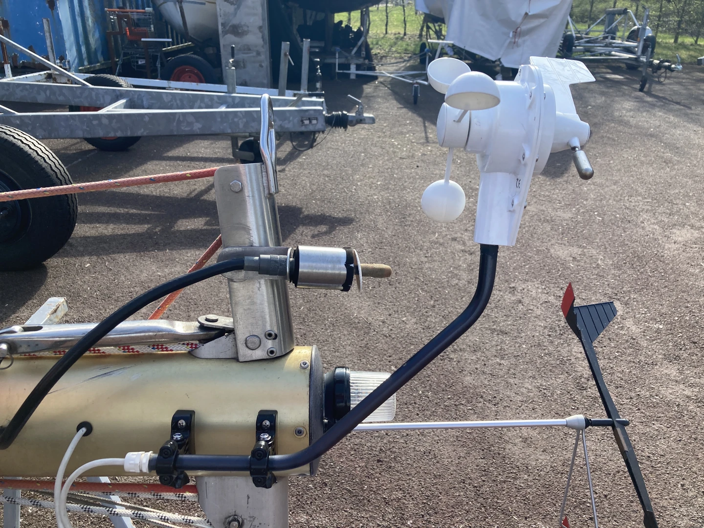 Weiße Wind-Masteinheit an einem schwarzen Gerätearm, mit zwei schwarzen gedruckten Gelenkhalterungen am liegenden Bootsmast montiert
