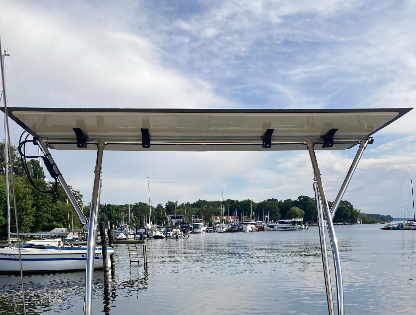 Montiertes flexibles Solarmodul mit vier schwarzen Halterungen am Edelstahlrahmen des Segelboots